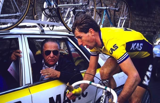 Historic photograph of a KAS professional road cyclist beside a team support car, featured on the Bike Box Sean bike box hire page.