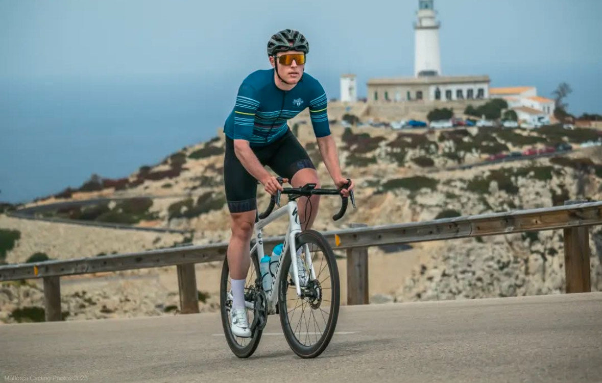 Road cyclist riding towards Cap de Formentor lighthouse in Mallorca, Spain, a popular cycling route for independent cycling holidays.