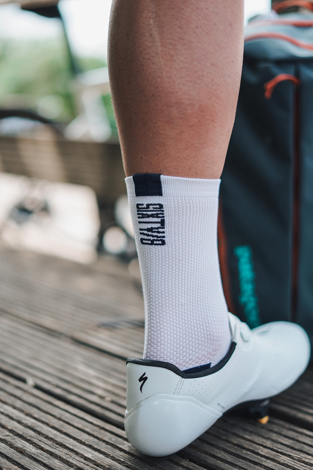 Close-up of SIXTY/8 white cycling socks with black logo worn with white road cycling shoes